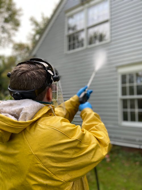 Free Back View of a Person Pressure Washing a House Stock Photo